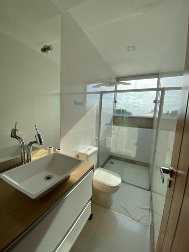 a white bathroom with a sink and a toilet at Pousada Ritec in Linhares