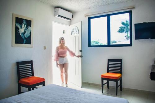 a woman is standing in a room with two chairs at Hotel Cupules in Mérida