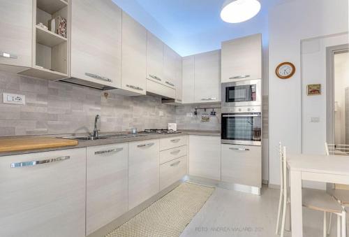 a white kitchen with white cabinets and a table at La reggia del mar - Genova Sturla, mare e Gaslini in Genova