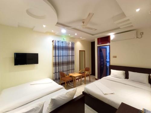 a room with two beds and a table and a tv at Sea Front Resort in Cox's Bazar