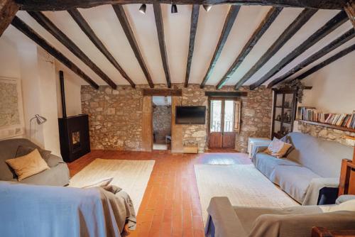 sala de estar con muebles y pared de piedra. en Casa Rural El Callís, en Vall de Bianya