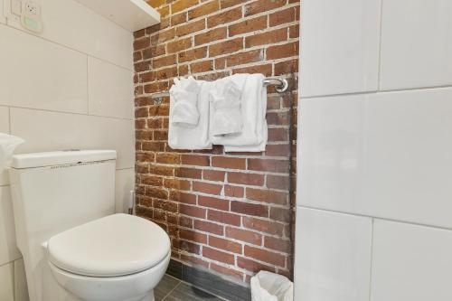 La salle de bains est pourvue de toilettes blanches et d'un mur en briques. dans l'établissement Chateau Des Tourelles, à Québec