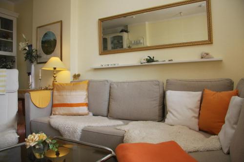 a living room with a couch with pillows and a mirror at Haus am Watt in Munkmarsch