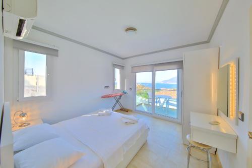 a white bedroom with a bed and a balcony at James Pansiyon Blue sea view villas Kaş Peninsula in Kas