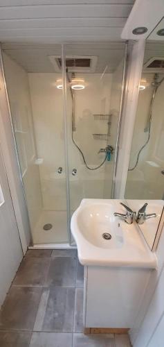 a bathroom with a white sink and a shower at Camping Vossenberg - op de Veluwe! in Epe