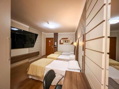 a hotel room with two beds and a flat screen tv at Goldmen Business Hotel in Cianorte