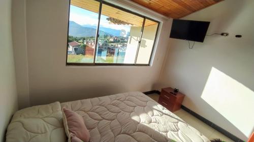 a bedroom with a bed and a large window at El Cerezo Casa de campo in Tópaga