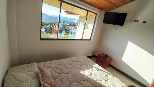 um quarto com uma cama e uma grande janela em El Cerezo Casa de campo em Tópaga