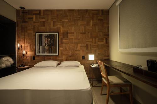 um quarto com uma cama branca e uma parede de madeira em LA HOTEL VOTUPORANGA em Votuporanga