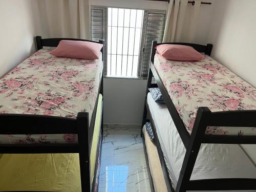 two bunk beds in a room with a window at Casa com piscina Guarujá Praia Pernambuco,Mar Casado in Guarujá