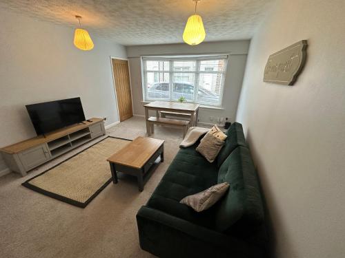 a living room with a green couch and a table at Cosy, 2 Bedroom Cottage in Guisborough Town Centre in Guisborough