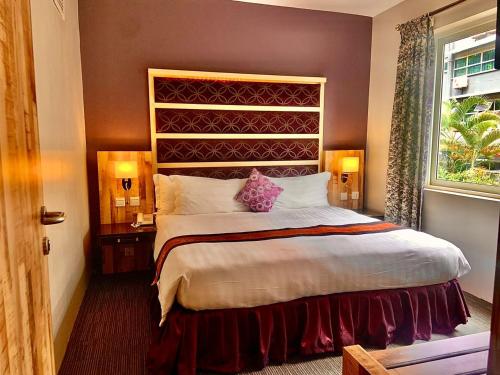 - une chambre avec un grand lit et une fenêtre dans l'établissement Arcadia Suites - Kampala, à Kampala
