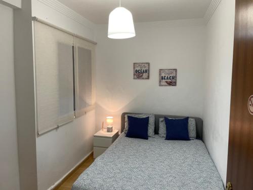 ein Schlafzimmer mit einem Bett mit blauen Kissen und einem Fenster in der Unterkunft Casa Oceano - 2 Bedroom Apartment in San Fernando