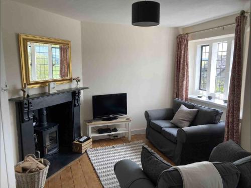 a living room with a couch and a fireplace at Cosy Arts & Crafts Cottage with stunning views in Brecon