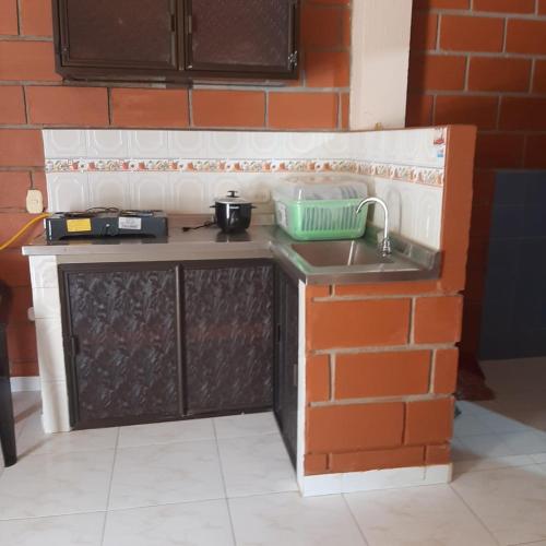 a miniature kitchen with a sink and a brick wall at Mi pueblo natal Aptos y habitaciones in Necoclí