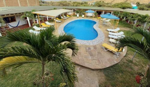 an overhead view of a swimming pool with chairs and umbrellas at Mancora y Sol in Máncora