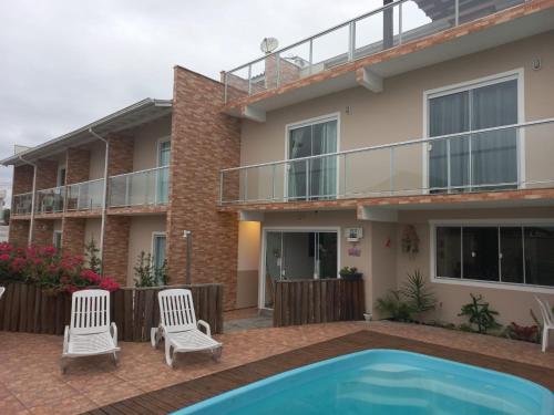 a house with a swimming pool and two chairs at Mares da Pinheira in Palhoça