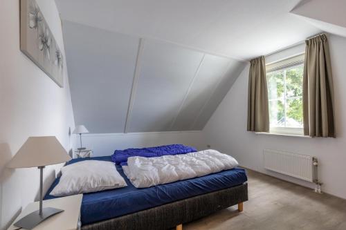 a bedroom with a blue and white bed and a window at Villa WaterGeluk ҉ in Susteren