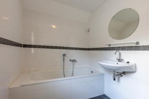 een witte badkamer met een bad en een wastafel bij Villa WaterGeluk ҉ in Susteren