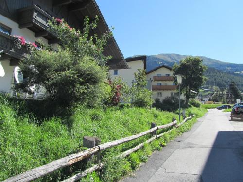 a road next to a house with a fence at Appartements Kroner in Nauders