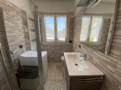 łazienka z umywalką, toaletą i oknami w obiekcie Casa Palabione w mieście Aprica