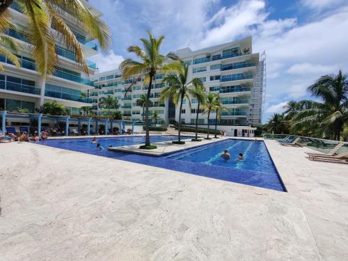 a resort swimming pool with palm trees and buildings at Hermoso apartamento en la playa in Cartagena de Indias