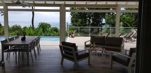 a patio with a table and chairs and a pool at La Vi la Bèl in Bouillante