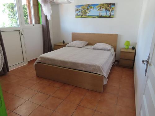 a bedroom with a bed and a tiled floor at TERRE DE BAS :L'île merveilleuse in Terre-de-Bas