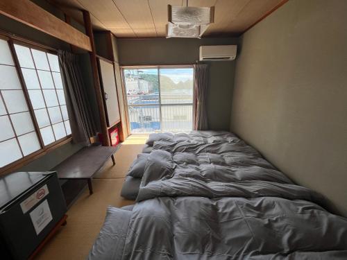 a bedroom with two beds and a large window at MAGURO BLDG チェックインはWhyKumano in Nachikatsuura