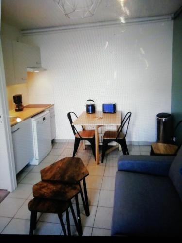 une cuisine avec une table et des chaises ainsi qu'une cuisine avec une table et un comptoir dans l'établissement Bel appartement avec jardin à 50m des plages du debarquement, à Bernières-sur-Mer