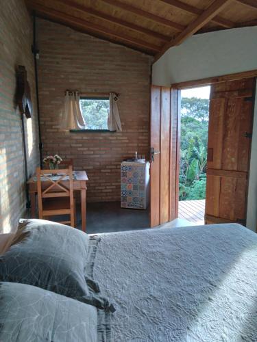 Pousada Canto da Lua - charme e vista incrível في كارانكاس: غرفة نوم بسرير ومكتب ونافذة