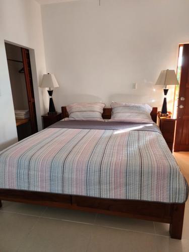 a bed with a striped comforter in a bedroom at Seremei Villas in Caye Caulker