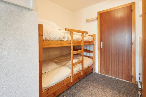 Cette chambre dispose de lits superposés avec 2 lits superposés et une porte. dans l'établissement Cosy studio for 5 near ski lift, HAMEAU D2, à Les Collons