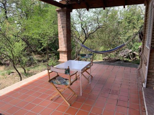 una hamaca en un porche con mesa y silla en Casa Iguana en Cuesta Blanca en Villa Icho Cruz