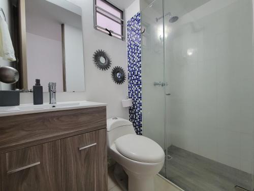 a bathroom with a toilet and a glass shower at Hermoso y comodo apartamento con Aire acondicionado y parqueo privado en unidad residencial - Jamundi in Jamundí