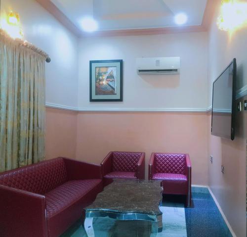 una sala de espera con 2 sofás rojos y TV en Haven Suites, Ikenegbu, en Owerri