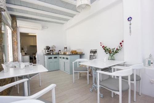 a restaurant with white tables and chairs and a kitchen at Hotel Spanelis in Mýkonos City