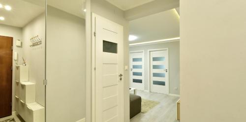 a hallway with white walls and a door with a chair at Apartament Centrum Śródmieście in Olsztyn