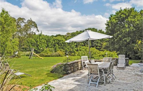 a table and chairs with an umbrella in a garden at Holiday Home Pont Aven Coteau De Keramperchec in Pont-Aven