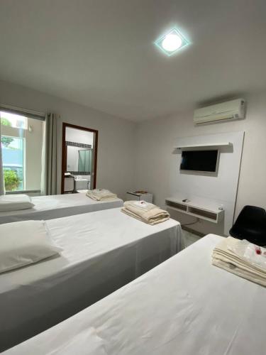 a bedroom with two beds and a tv and a window at Pousada Ritec in Linhares