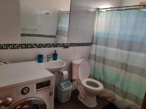 a bathroom with a toilet and a sink and a washing machine at Cabaña Nuevo Amanecer in San José de la Mariquina