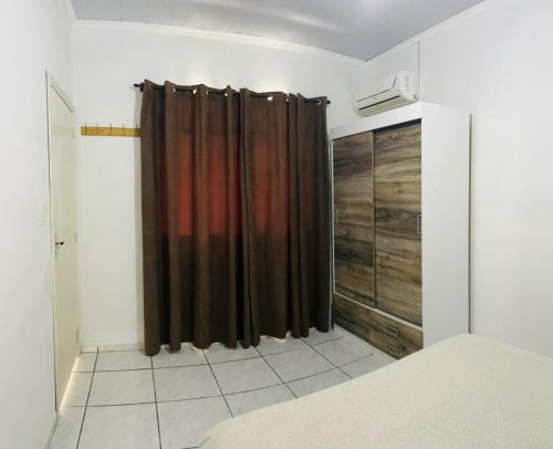 1 dormitorio con cortina marrón y armario en Casa em Bombinhas Praia do Mariscal, en Bombinhas