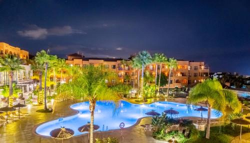 um resort com piscina e palmeiras à noite em Hotel Oh Nice Caledonia em Estepona