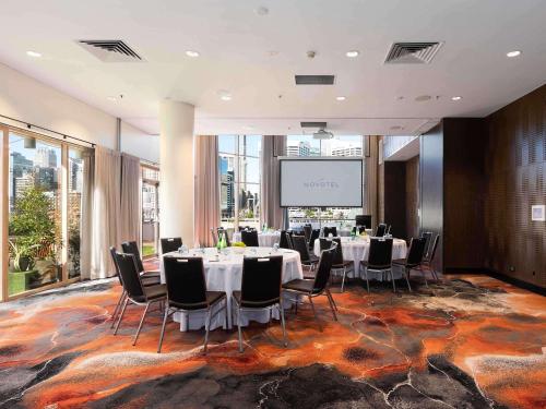 a conference room with tables and chairs and a projection screen at Novotel Sydney Darling Harbour in Sydney