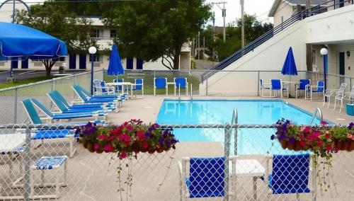 a swimming pool with blue chairs and blue umbrellas at Fields Park Motel in Wisconsin Dells