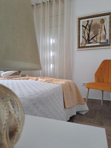 a white bedroom with a bed and a chair at CASA VAGOS in Nazaré
