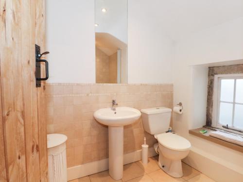 a bathroom with a sink and a toilet and a mirror at Dragon Cottage in Bakewell