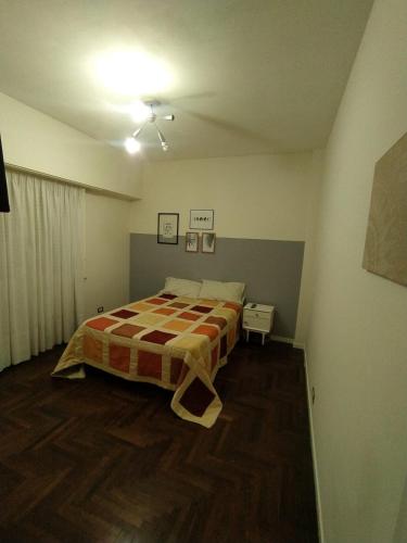 1 dormitorio con 1 cama con manta a cuadros en Departamento en Mar del Plata en Mar del Plata
