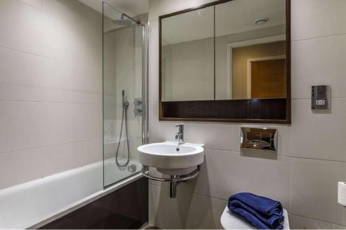 y baño con lavabo, ducha y espejo. en Private Room Available in Spacious High Rise Apartment with Park & City View en Dublín