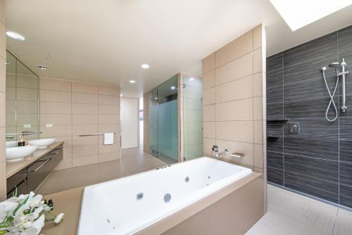 uma casa de banho com uma banheira grande e um lavatório em 180 Degrees em Cannonvale